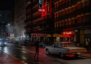 Timothée Chalamet as Bob Dylan walking across the street at night, neon lights cars and retro atmosphere.