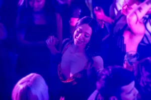 Atmospheric moment of Anora dancing and the purple-blue lights.